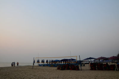 People on beach against clear sky during sunset