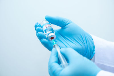 Close-up of hand holding blue over white background