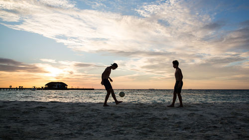Silhouette people on beach against sky during sunset