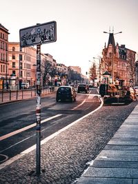 Road sign on city street against sky