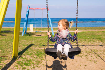 Girl sitting on swing at playground