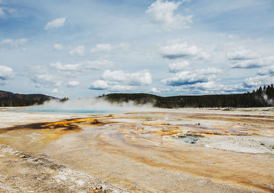 Scenic view of hot springs at yellowstone national park against cloudy sky