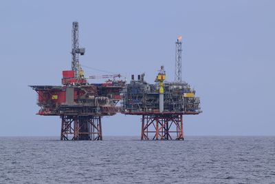 Drilling rig in sea against clear sky