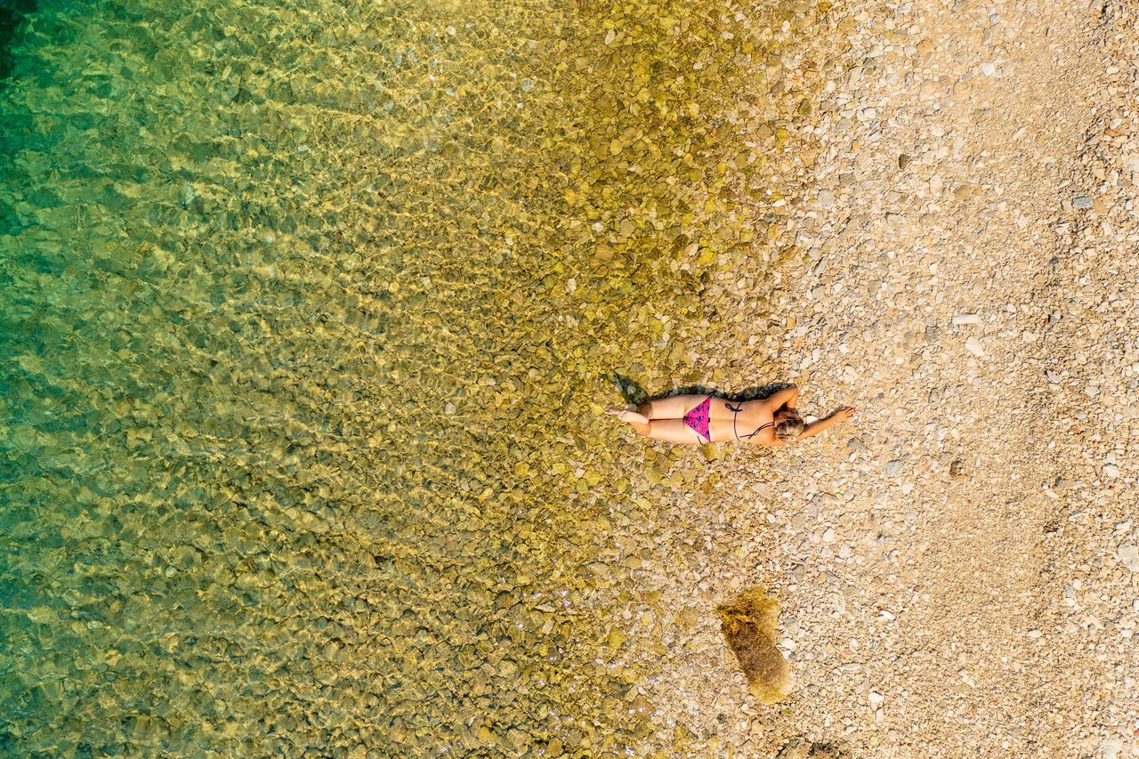 HIGH ANGLE VIEW OF WOMAN LYING ON SHORE