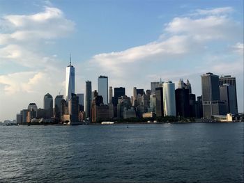 City at waterfront against cloudy sky