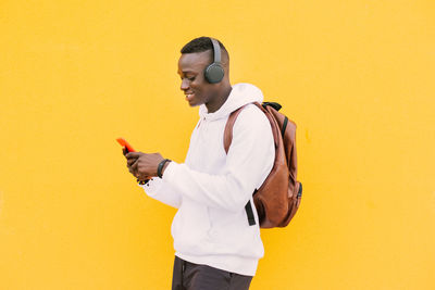 Smiling young man standing against yellow background