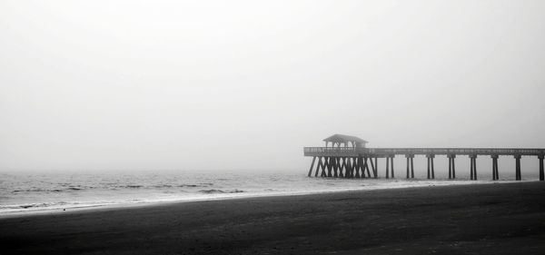 Pier on beach against sky