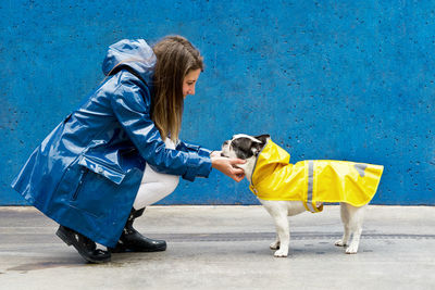 Happy woman wearing raincoat stroking dog