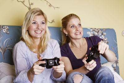 Two young women playing video game in bedroom