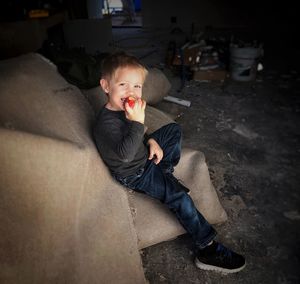 Portrait of boy eating while sitting on floor