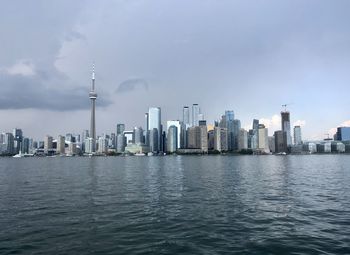 Sea by modern buildings against sky in city