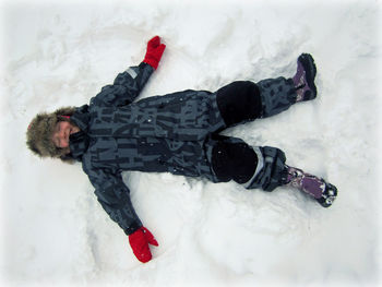 Directly above shot of girl lying down on snow covered field