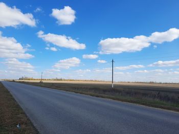 Empty road by land against sky