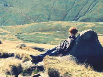 Rear view of woman sitting on mountain