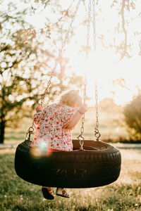 Rear view of girl sitting on tire swing in park