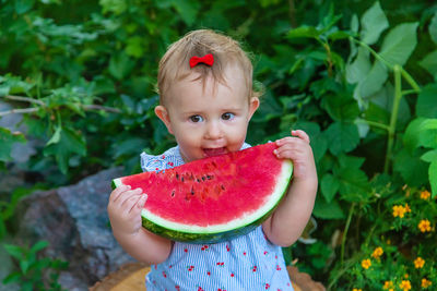 Cute girl eating watermelon against plants
