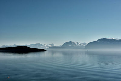 Scenic view of lake and mountains against clear blue sky