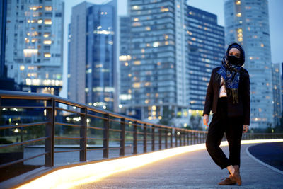 Full length of man standing on railing against buildings in city