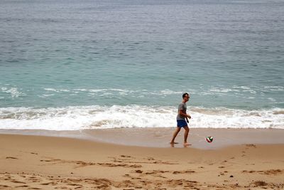 Full length of man playing football at beach