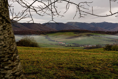 Scenic view of field by mountains against sky