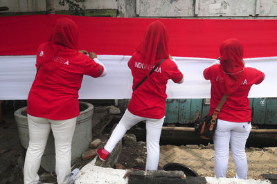 Rear view of men standing against red wall