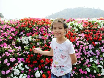 Smiling girl standing by flowering plants