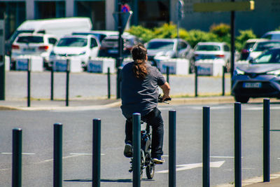 Rear view of man riding bicycle on city street