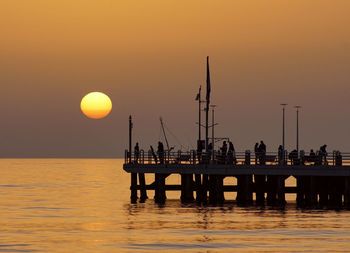 Silhouette pier over sea against sky during sunset