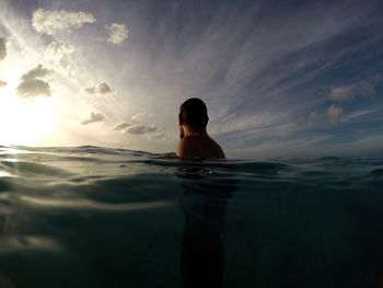 Man swimming in sea against sky