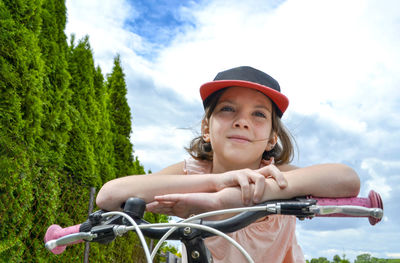 Portrait of young woman riding bicycle against sky