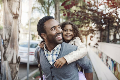 Happy father giving piggyback ride to daughter