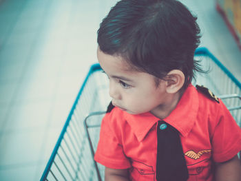 Close-up of cute boy sitting on shopping cart