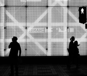Silhouette people standing against wall