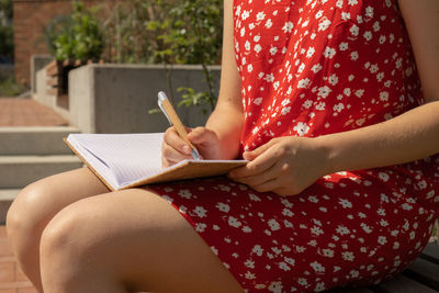 Midsection of woman writing in book