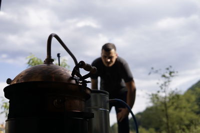 Low angle view of man holding camera against sky