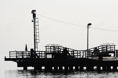 Silhouette cranes against clear sky