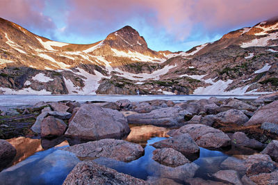 Pink dawn light over mt. toll and partially frozen blue lake in colorado's indian peaks wilderness. 