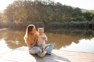 Smiling young mother playing with baby boy 1 year old wear casual clothes over nature background