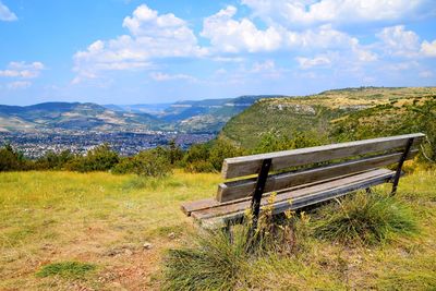 Empty bench on field against sky