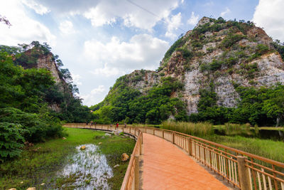 Bridge over river by trees against sky