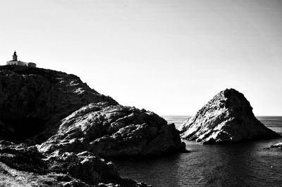 Rock formations by sea against clear sky