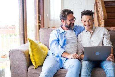 Smiling father using laptop with son