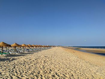 Scenic view of beach against clear blue sky