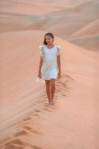 Full length of woman walking on sand dune