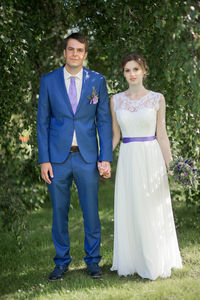 Portrait of bride and groom standing at park