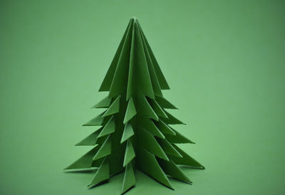 Green origami christmas tree on a green background.