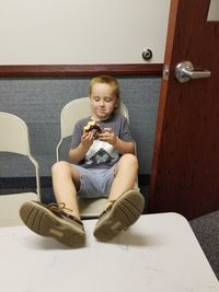 Portrait of a smiling young woman sitting on door