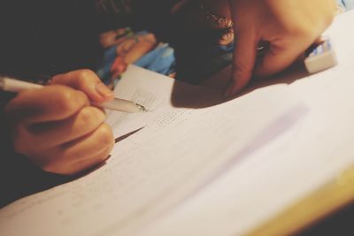 Cropped hand writing in paper at office