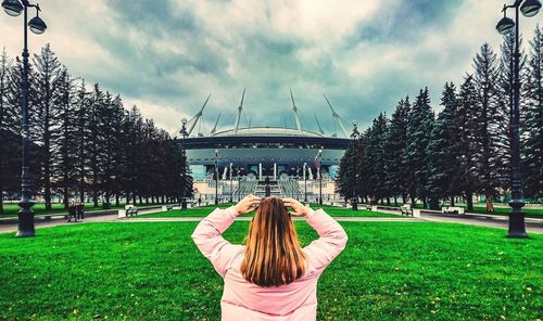 Rear view of woman standing in park against sky