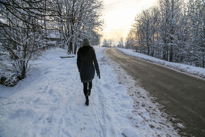 Rear view of man walking on snow covered landscape